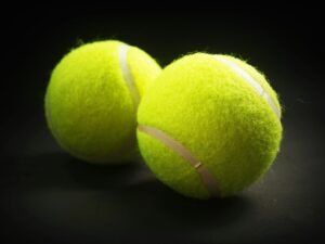 pexels-photo-226586-226586 Close-up of two tennis balls with a vibrant yellow color on a dark background.